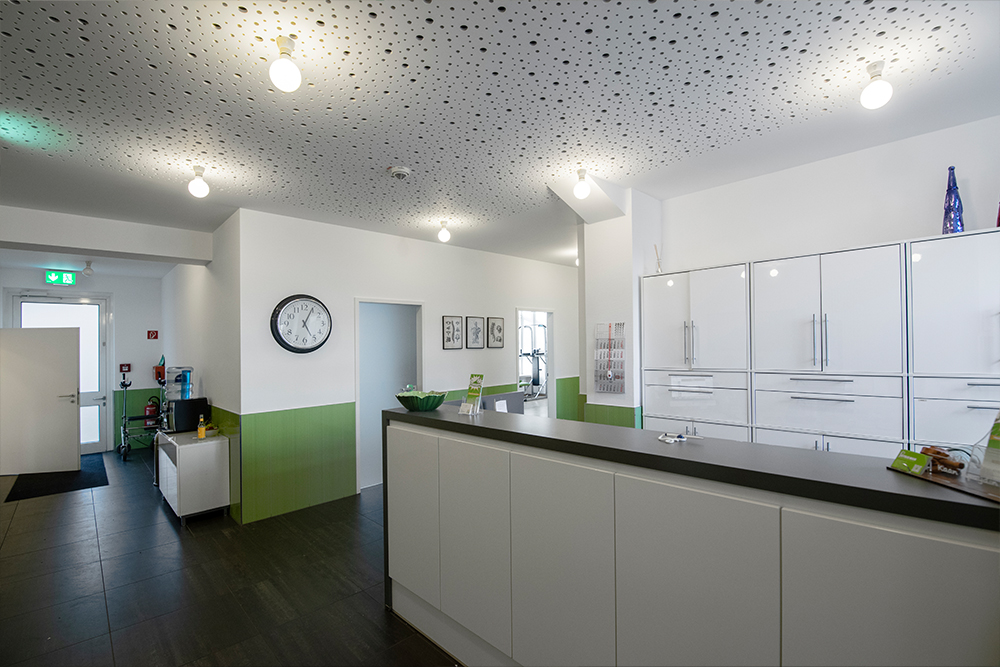 Heller Empfangsbereich der PHYSIOMAN Praxis mit grünen Akzenten