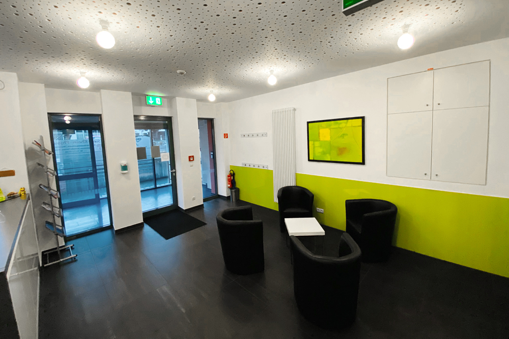 Modernes Wartezimmer mit Clubsesseln und grüner Wandgestaltung